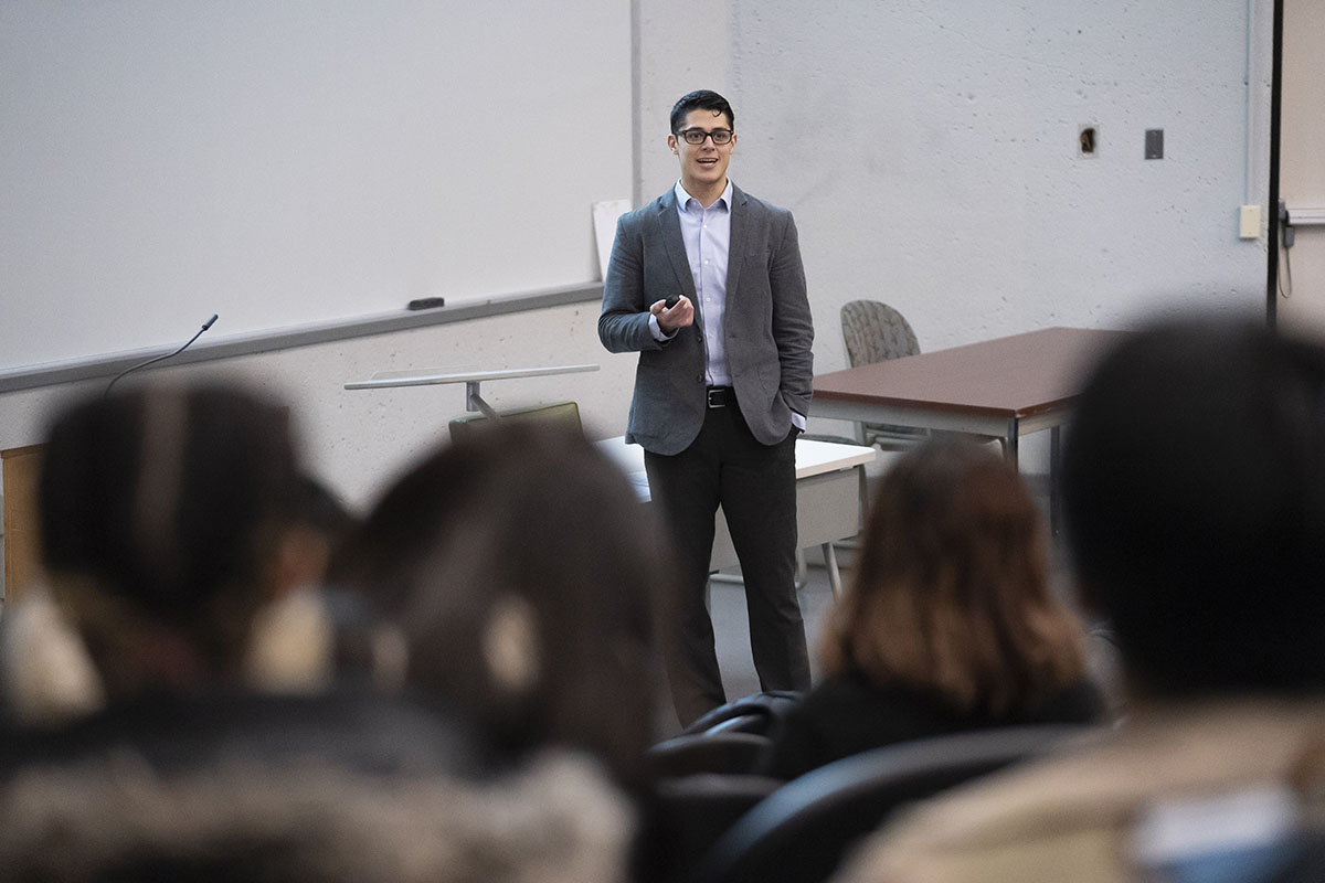 man lecturing at front of auditorium